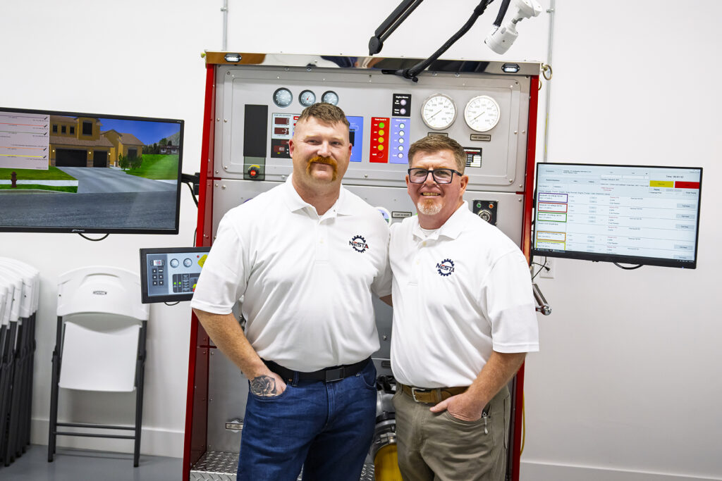 Two Instructors Standing by Firefighting Control Panel